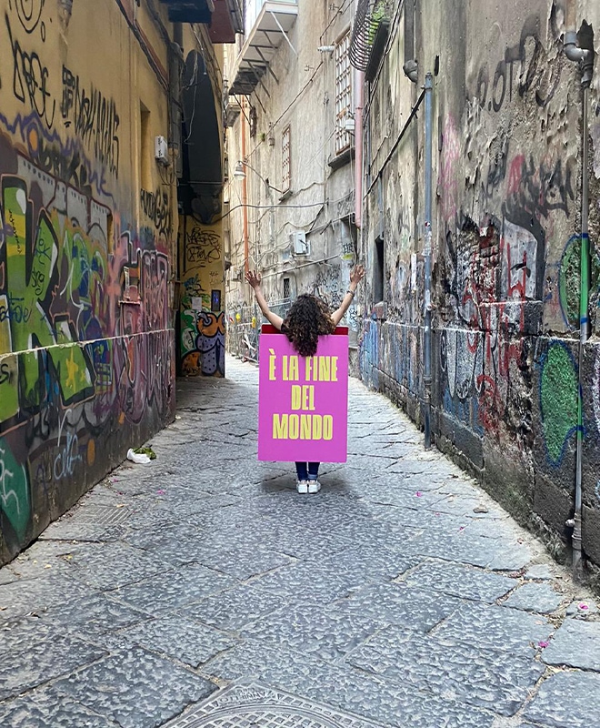 Una ragazza sandwitch tra i vicoli di Napoli con indosso il cartellone 